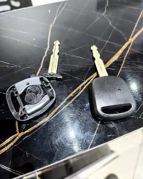 Toyota remote key with a broken shell (left, CR1220 battery visible) and the same key in a new shell (right), repaired by Carkey Masters